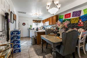 Dining area with a chandelier, light tile patterned floors, and a textured ceiling