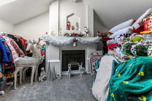 Walk in closet featuring vaulted ceiling, carpet flooring, and a fireplace