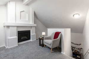 Sitting room featuring vaulted ceiling with beams, a fireplace, and carpet flooring
