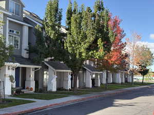 View of front facade with stucco siding, roof with shingles, a front lawn, and a residential view