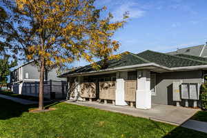 Back of property with roof with shingles, stucco siding, and a lawn