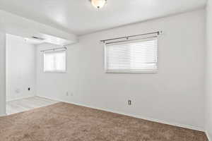 Unfurnished room featuring light carpet and baseboards