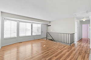 Unfurnished room with light wood finished floors and attic access