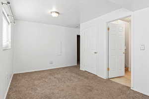 Unfurnished bedroom with light carpet and baseboards
