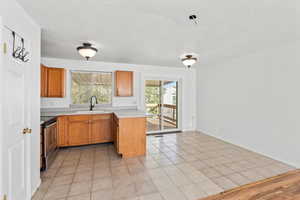 Kitchen with light countertops, light tile patterned floors, stainless steel electric range, and brown cabinets