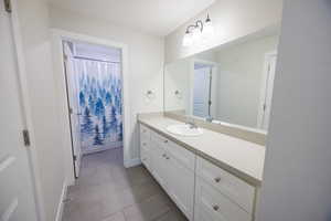 Full bath featuring vanity, light tile patterned floors, and curtained shower
