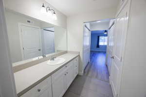 Bathroom with vanity, dark tile patterned flooring, and a ceiling fan