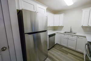 Kitchen featuring appliances with stainless steel finishes, light countertops, light wood-style floors, white cabinets, and a textured ceiling
