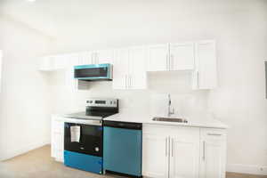 Kitchen with white cabinets, appliances with stainless steel finishes, light wood-type flooring, and light stone countertops