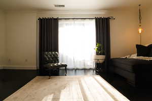 Bedroom with ornamental molding and wood finished floors