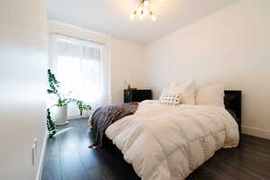 Bedroom with dark wood-type flooring and a chandelier