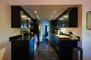 Kitchen with dark cabinets, stainless steel appliances, finished concrete flooring, recessed lighting, and modern cabinets