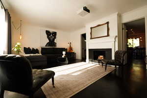 Living room with a lit fireplace, ornamental molding, and dark wood-style floors