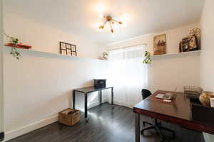 Home office with dark wood finished floors, a textured ceiling, a textured wall, and a chandelier