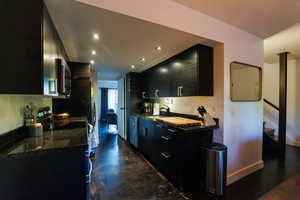 Kitchen with dark cabinetry, recessed lighting, concrete floors, dark stone counters, and stainless steel appliances
