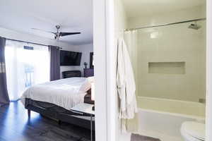 Full bath with ensuite bathroom, shower / bath combination with curtain, wood finished floors, and a ceiling fan