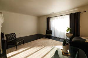 Sitting room featuring dark wood-style flooring and crown molding