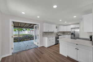 Kitchen with white cabinets, appliances with stainless steel finishes, light stone countertops, dark wood finished floors, and recessed lighting
