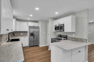 Kitchen featuring appliances with stainless steel finishes, a peninsula, recessed lighting, white cabinets, and dark wood-type flooring