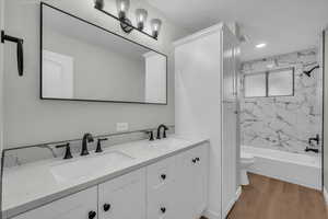 Bathroom with double vanity, light wood finished floors, and shower / washtub combination