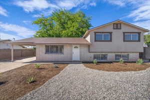 Split level home with brick siding, stucco siding, a carport, and concrete driveway
