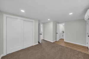 Basement with carpet, recessed lighting, and an AC wall unit