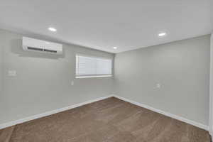 Basement with carpet floors, recessed lighting, and an AC wall unit