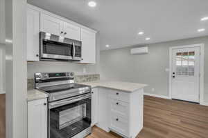 Kitchen with appliances with stainless steel finishes, white cabinetry, light wood-style floors, recessed lighting, and a peninsula