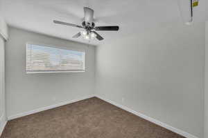 Empty room with dark colored carpet and ceiling fan
