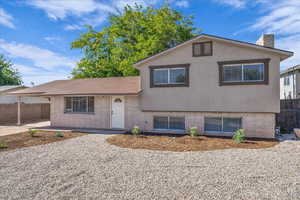 Split level home featuring a chimney, brick siding, and stucco siding