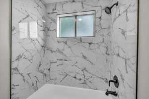 Bathroom featuring a combined bath / shower with marble appearance