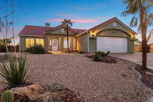 Mediterranean / spanish-style home featuring a tiled roof, driveway, a chimney, and stucco siding
