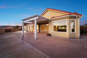 Back of property at dusk with a pergola, stucco siding, a fenced backyard, and a tiled roof