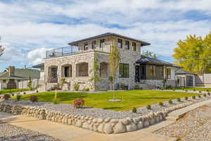 View of front of home with stone siding, a front lawn, and a garage