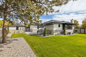 Rear view of property with stone siding, stucco siding, a chimney, a standing seam roof, and a metal roof