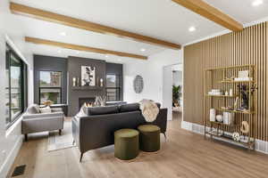 Living room with beam ceiling, plenty of natural light, light wood-type flooring, a fireplace, and recessed lighting