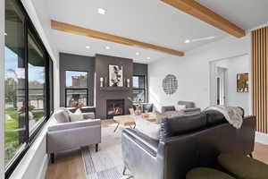 Living room with beam ceiling, recessed lighting, light wood-style flooring, and a fireplace