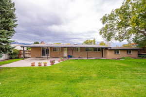 Rear view of property featuring brick siding, a patio area, and a chimney