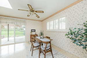 Dining space featuring ornamental molding, plenty of natural light, ceiling fan, wallpapered walls, and a skylight