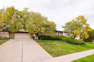 Front view of property featuring driveway, brick siding, and a garage