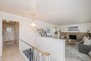 Hall featuring crown molding, wallpapered walls, light patterned floors, and an upstairs landing
