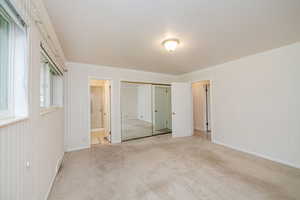 Unfurnished bedroom with ensuite bathroom, carpet, ornamental molding, and a closet