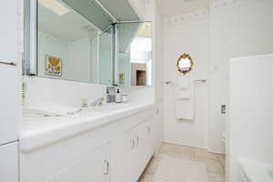 Full bath with vanity, wallpapered walls, a bathtub, light tile patterned flooring, and tile walls