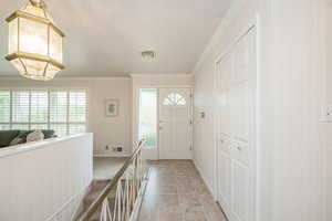 Entrance foyer with ornamental molding, plenty of natural light, and light tile patterned flooring