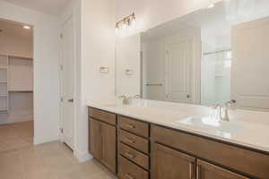 Bathroom with double vanity, a walk in closet, a stall shower, light tile patterned floors, and recessed lighting
