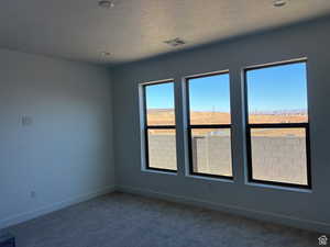 Empty room featuring dark colored carpet and baseboards