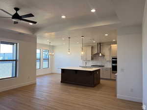 Kitchen featuring pendant lighting, a center island with sink, tasteful backsplash, a kitchen breakfast bar, and a chandelier