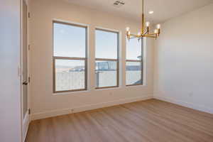 Spare room with light wood-style flooring, a chandelier, and recessed lighting