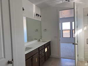 Bathroom with light tile patterned floors, double vanity, and light carpet