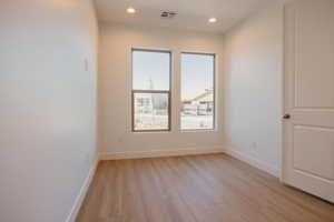 Empty room with light wood finished floors and recessed lighting